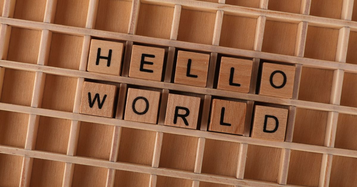 Wooden blocks with letters spelling HELLO WORLD on a wooden grid background, ideal for language concepts.